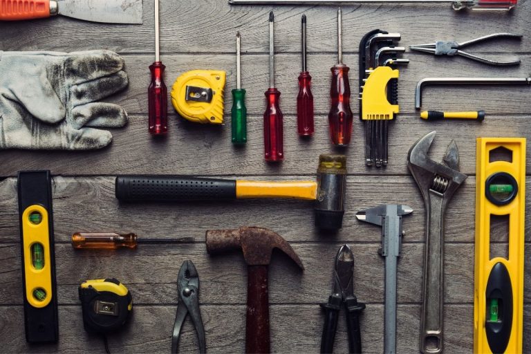 An assortment of tools, such as hammers and saws, laid out on a wooden table, showcasing a well-organized workspace.
